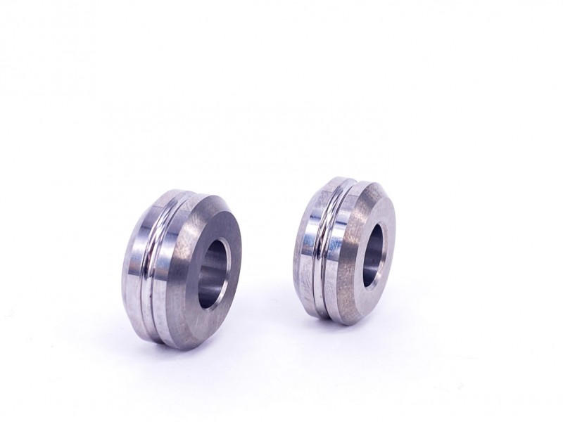 A pair of tungsten carbide rollers with a central hole and stepped design
